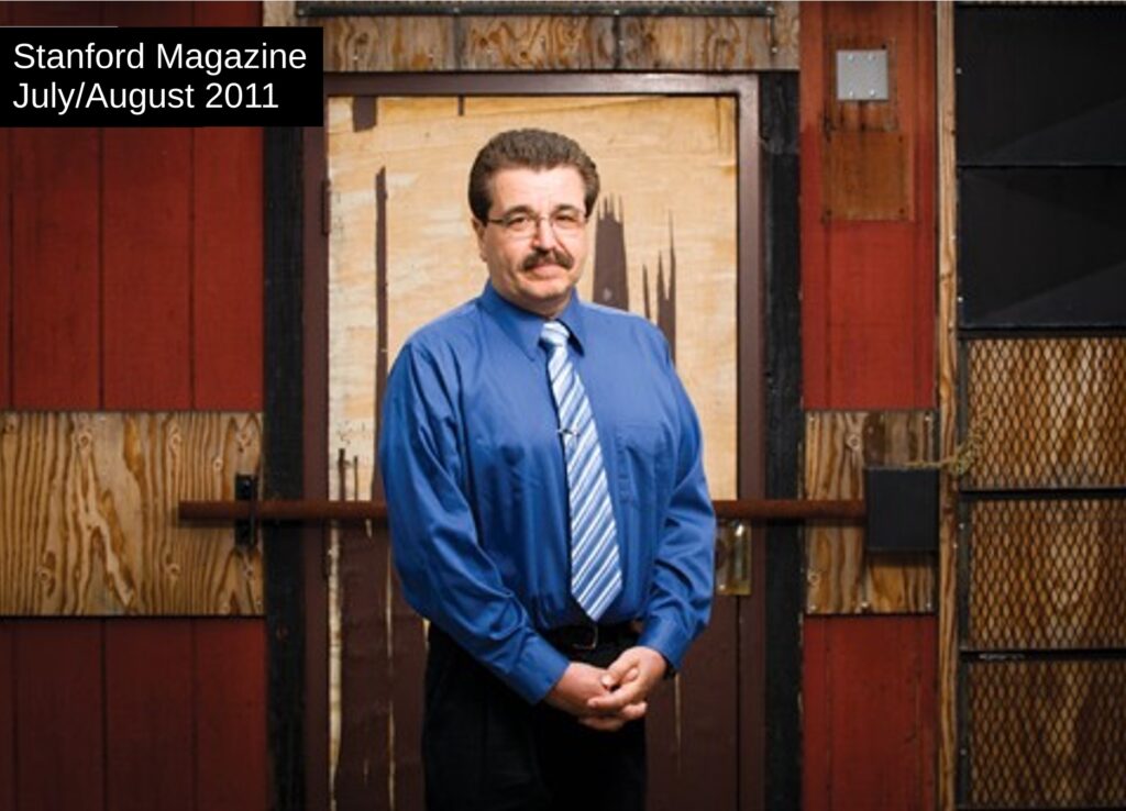 Rich in front of Oakland classroom. The damaged door is covered by a security bar.